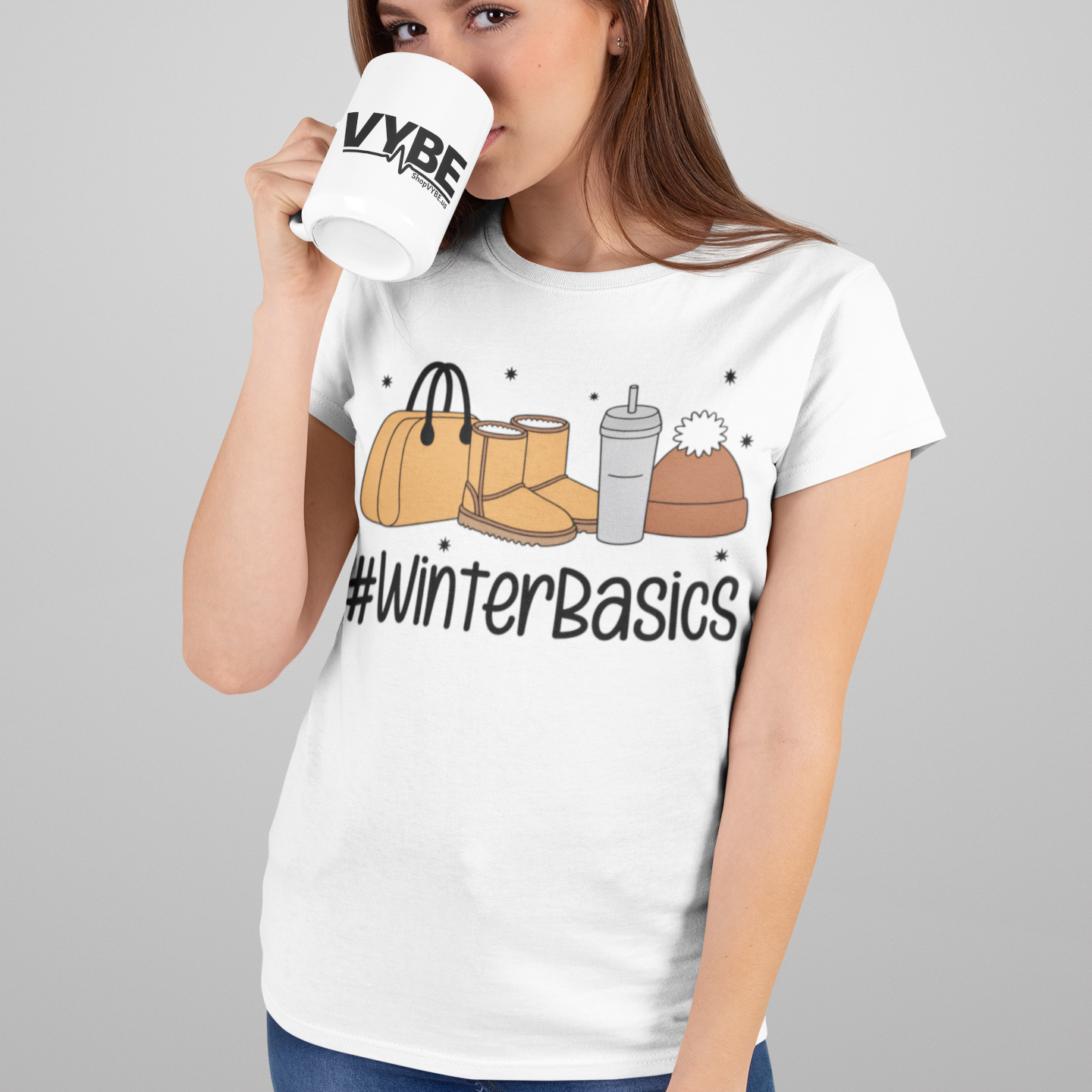 Woman wearing a white t-shirt with '#WinterBasics' design, holding a mug.