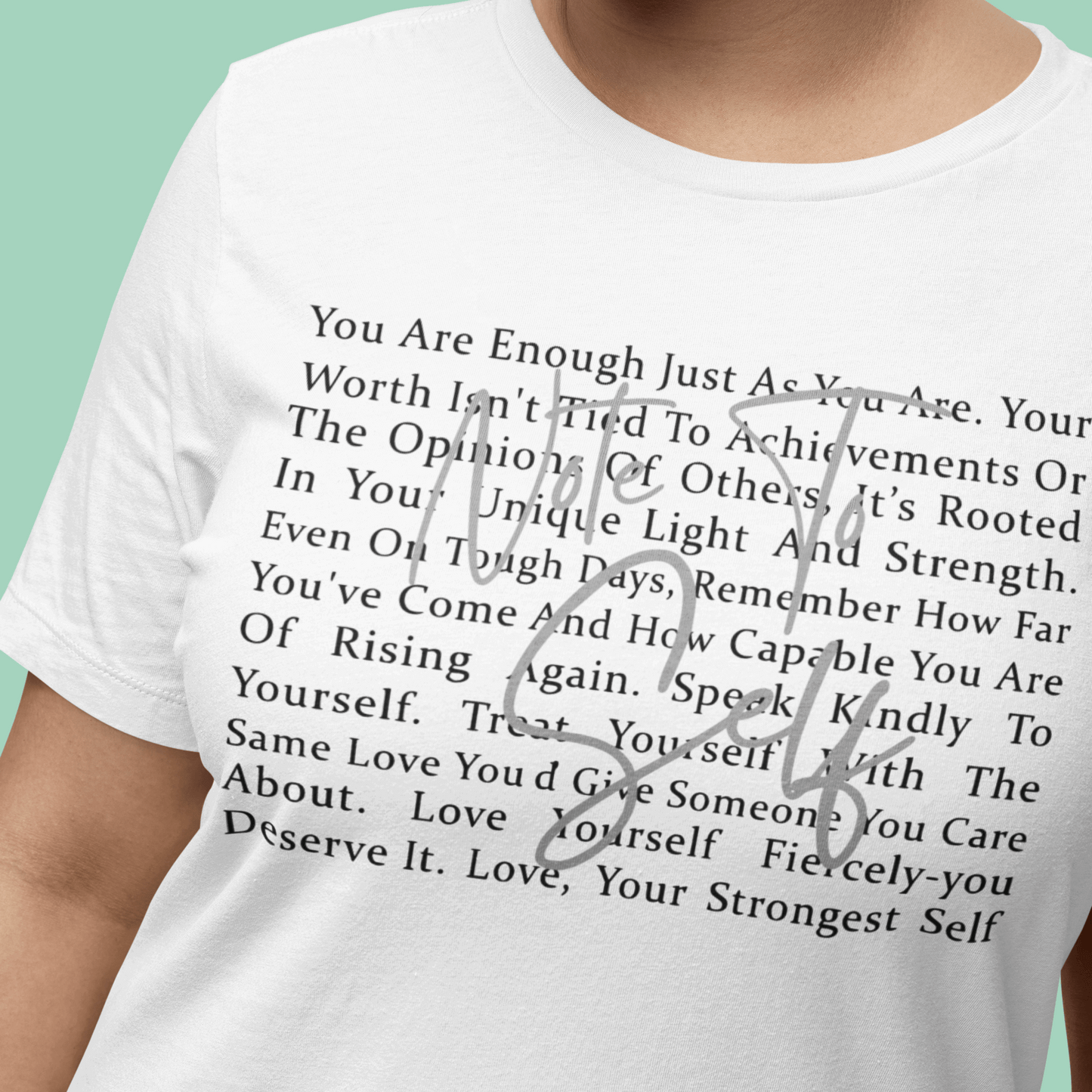 Person wearing a white t-shirt with an inspirational message printed on it against a green background