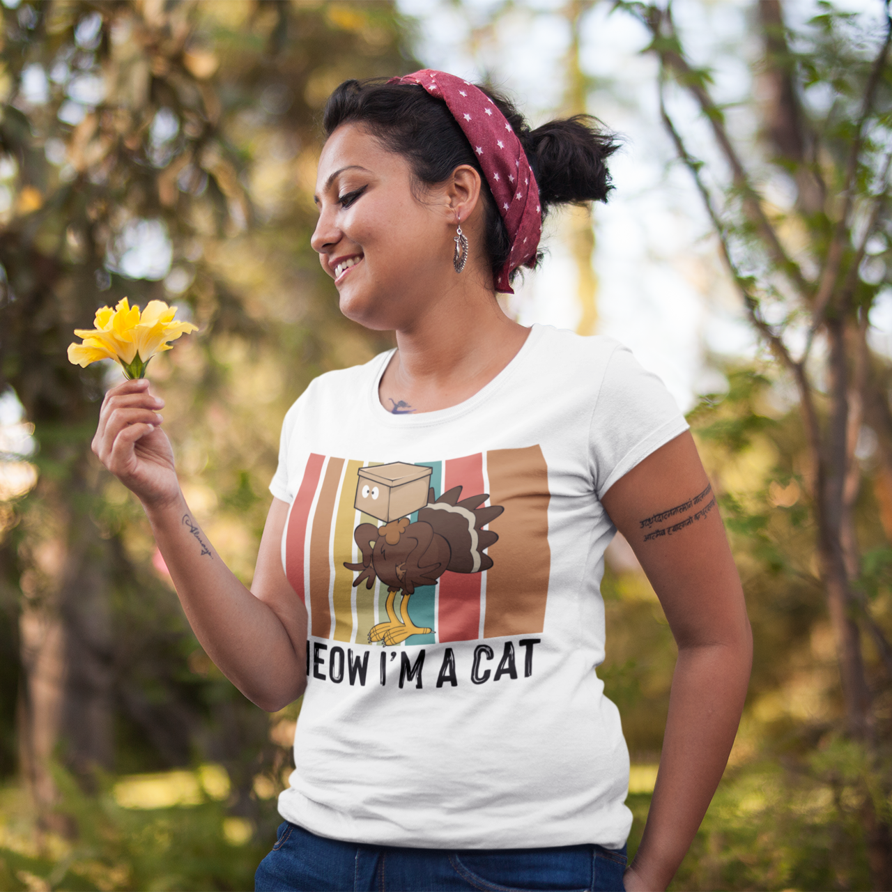 Woman holding flowers outdoors wearing a t-shirt with a graphic design.