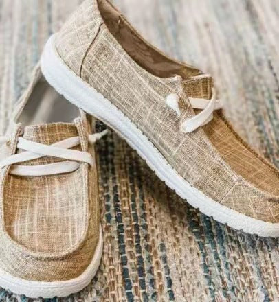 Pair of beige shoes with white soles on a textured surface