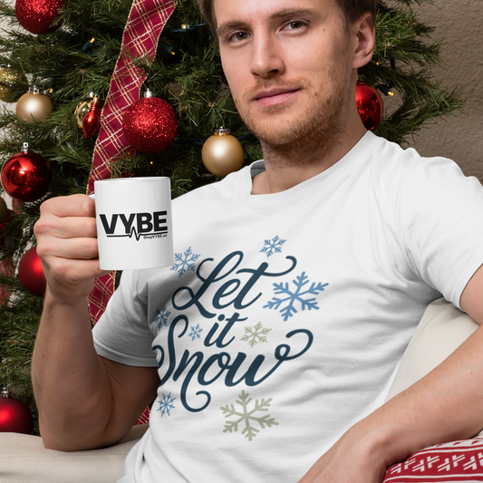 Man holding a mug with 'VYBE' in front of a Christmas tree