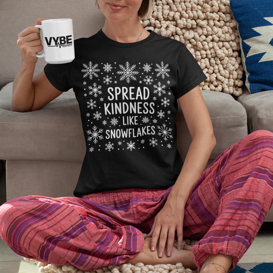 Person wearing a black t-shirt with 'Spread Kindness Like Snowflakes' text, sitting on a colorful rug.