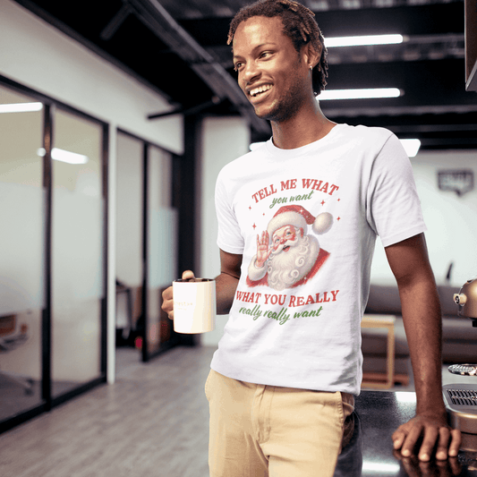 Man in a modern office holding a coffee cup, wearing a t-shirt with a Christmas design.