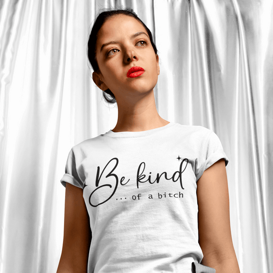 Woman wearing a white t-shirt with 'Be kind... of a bitch' text against a white curtain background