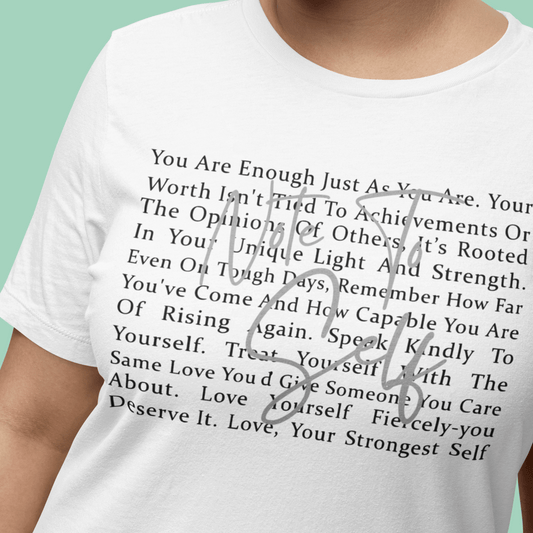 Person wearing a white t-shirt with an inspirational message printed on it against a green background