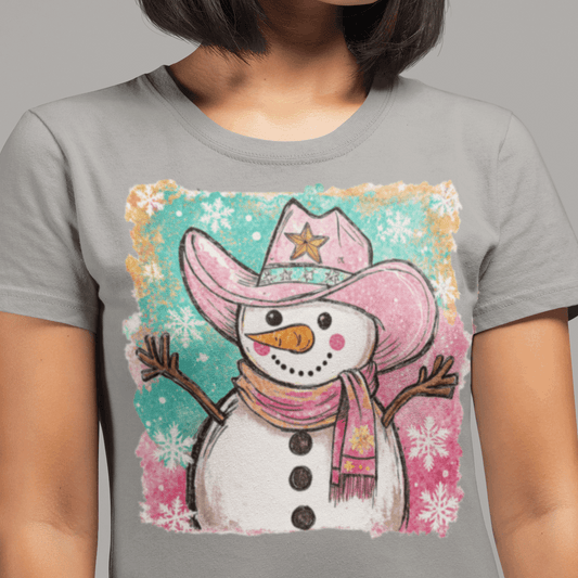 Person wearing a gray t-shirt with a snowman graphic in a pink cowboy hat and scarf.