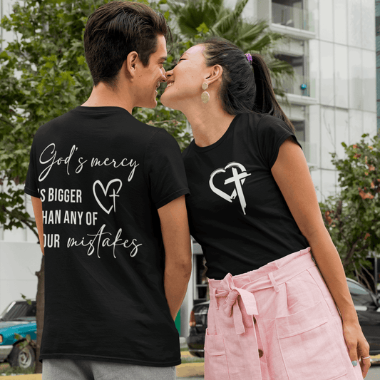 Two people wearing black t-shirts with text and graphics, standing close together outdoors.