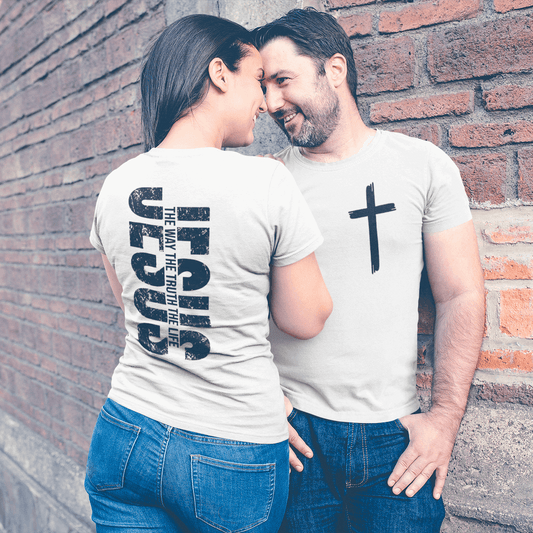 Two people standing close together against a brick wall, wearing matching t-shirts with text and a cross design.