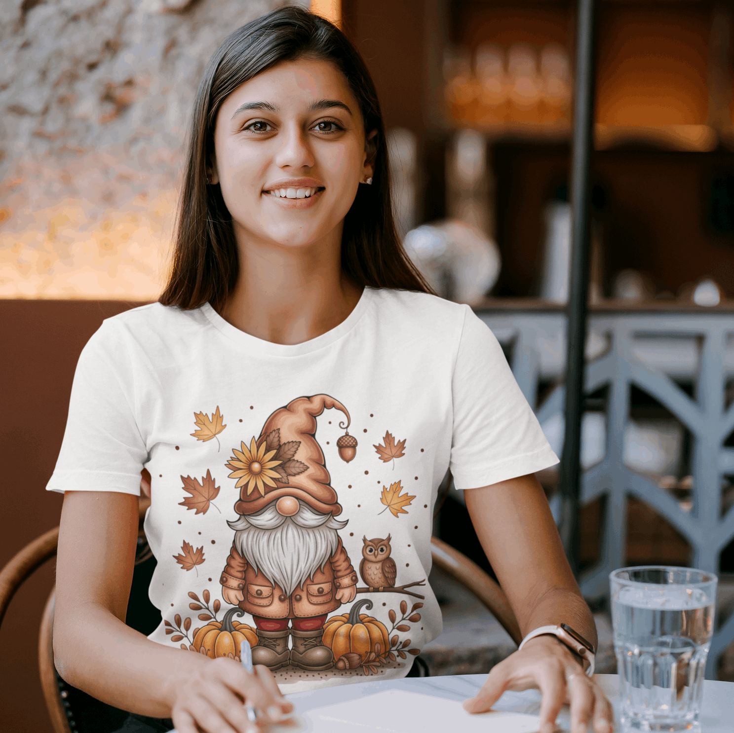 Woman wearing a white t-shirt with a gnomes and pumpkins design in a casual setting.