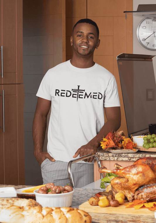 Man wearing a 'REDEEMED' t-shirt in a kitchen with a roasted turkey and感恩节 decorations.