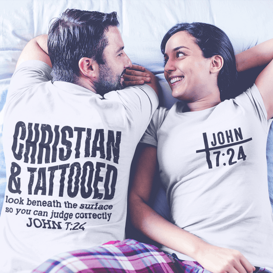 Two people lying on a bed wearing t-shirts with text.