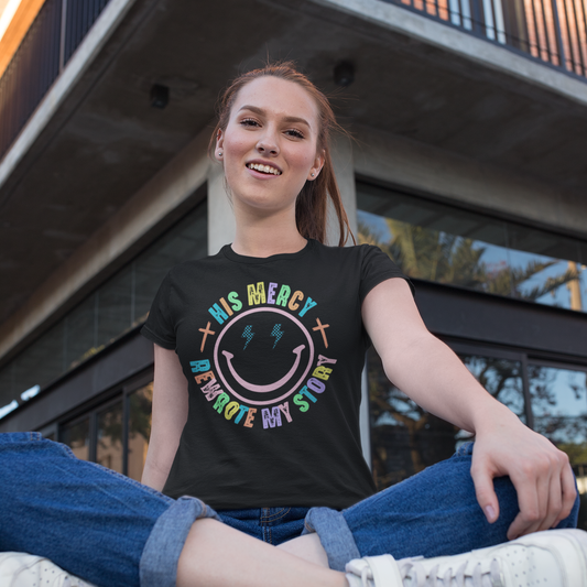 Person sitting on a bench wearing a black t-shirt with a colorful smiley face design.