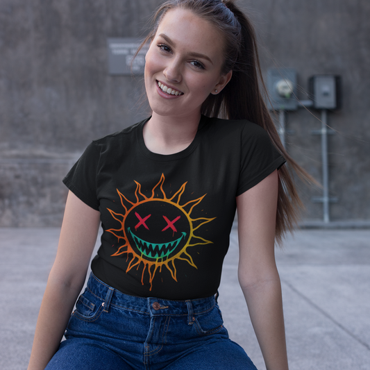 Woman wearing a black t-shirt with a colorful sun graphic design, sitting on a concrete surface.