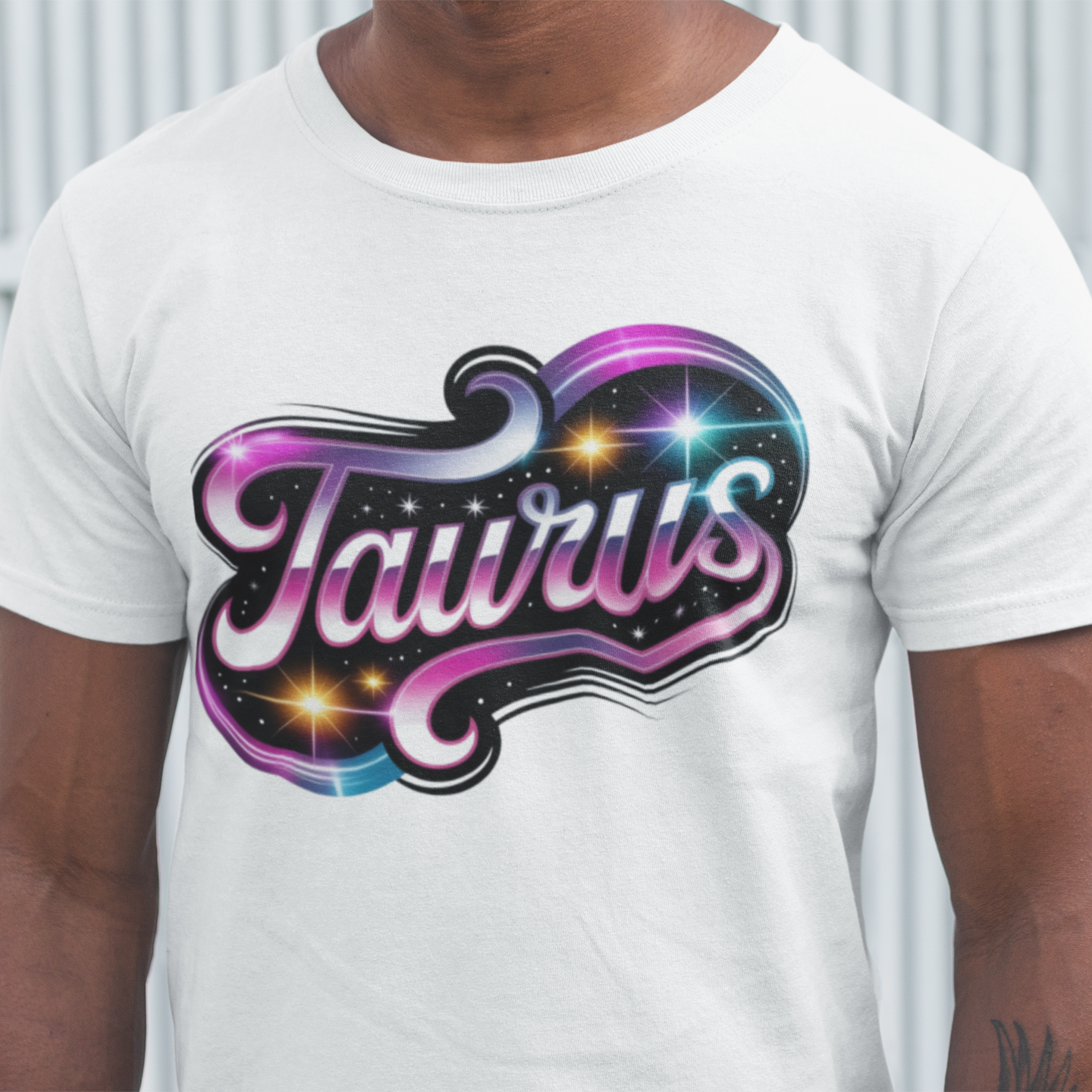 Person wearing a white t-shirt with 'Taurus' design in colorful letters.