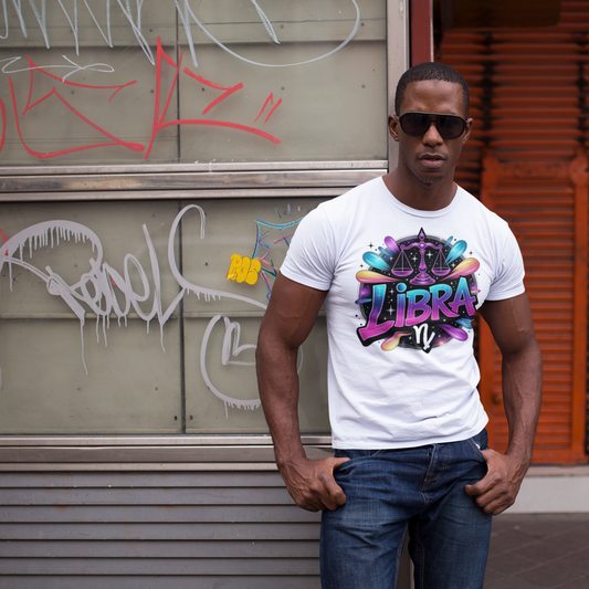 Man wearing a white t-shirt with colorful graphics and text, standing in front of a graffiti-covered wall.