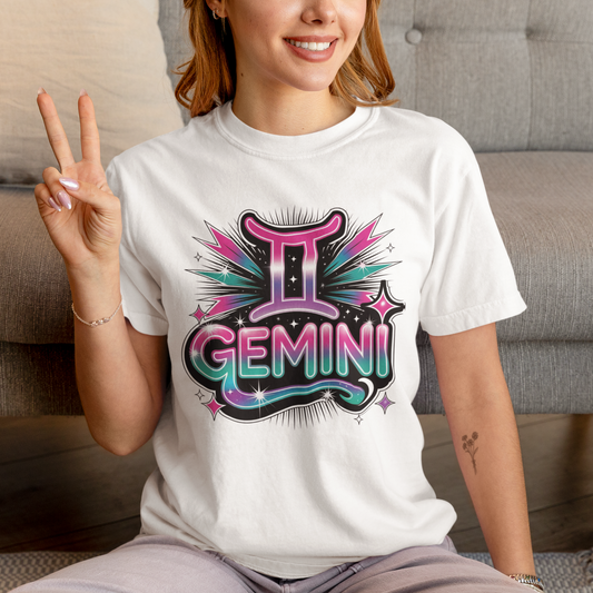 Person wearing a white t-shirt with 'Gemini' design, sitting on a couch.