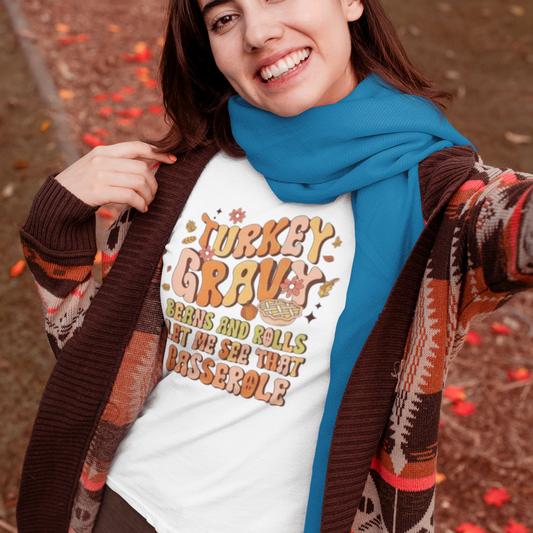 Woman wearing a 'Turkey Gravy' shirt with a blue scarf outdoors.