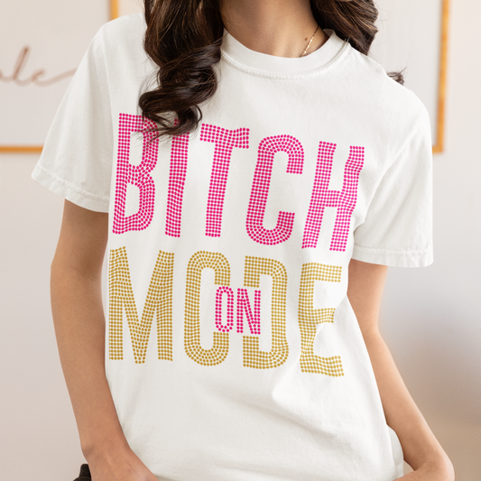 Person wearing a white t-shirt with 'Bitch Mode' text in pink and gold.