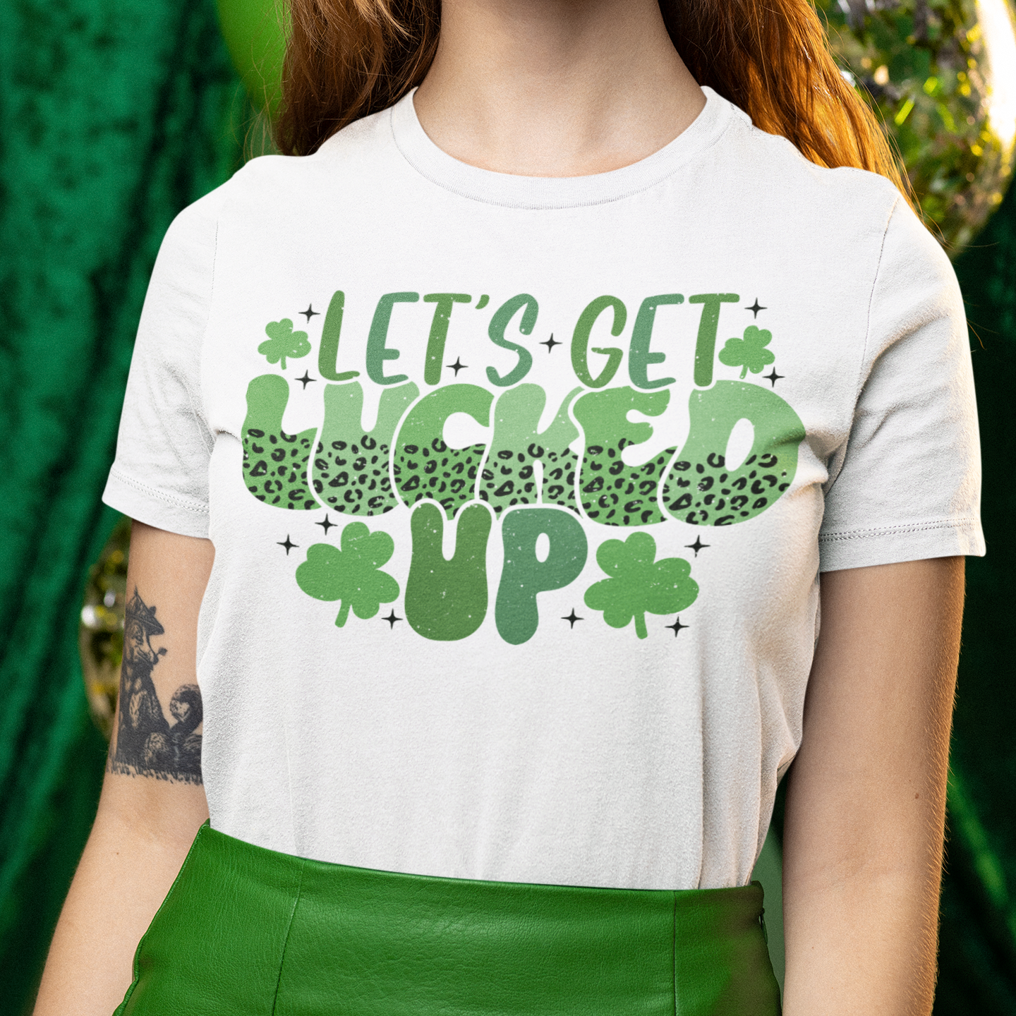Person wearing a white t-shirt with green text and shamrock design, standing against a green background.