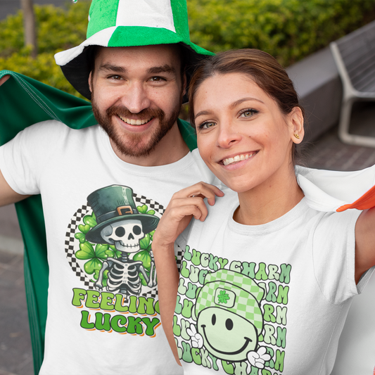 Two people wearing white t-shirts with green and orange designs, standing outdoors.
